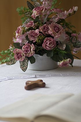 Blumenstrauss, Kreuz und Buch auf einem Tisch