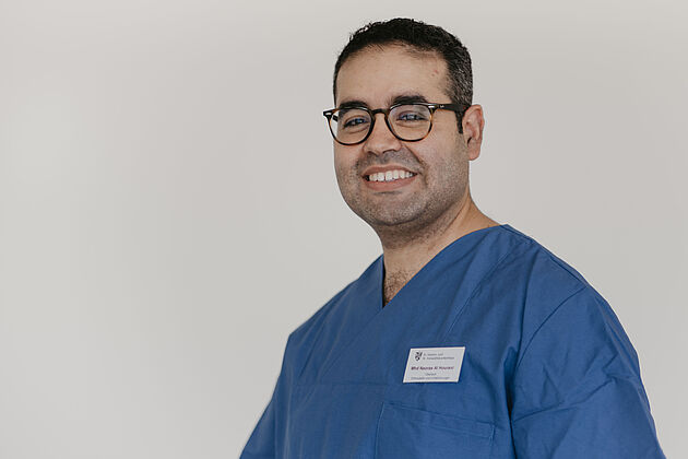 Mann im blauen Kittel lächelt in die Kamera