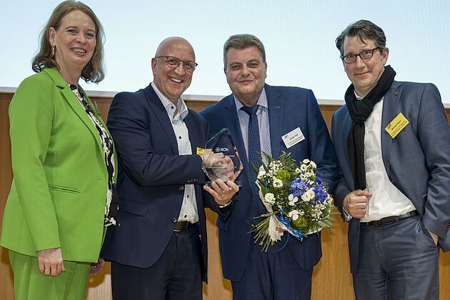 3 Männer und 1 Frau lächeln in die Kamera bei einer Preisübergabe